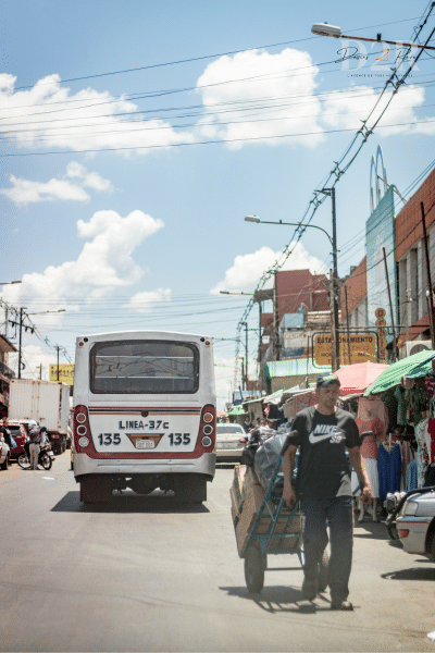 Photo d'une rue au Paraguay, on y voit les transports locaux : un bus et un marché sur le côté