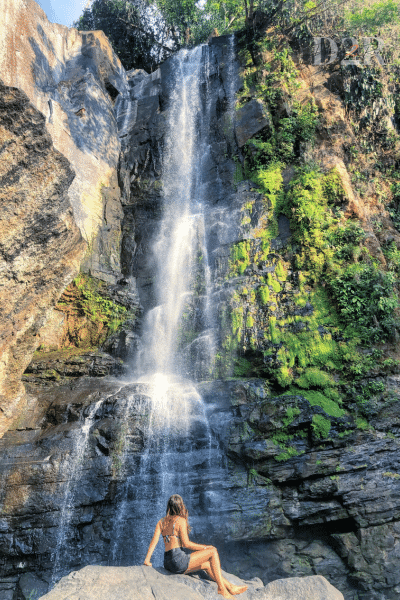 image d'une femme qui regarde une cascade dans la roche